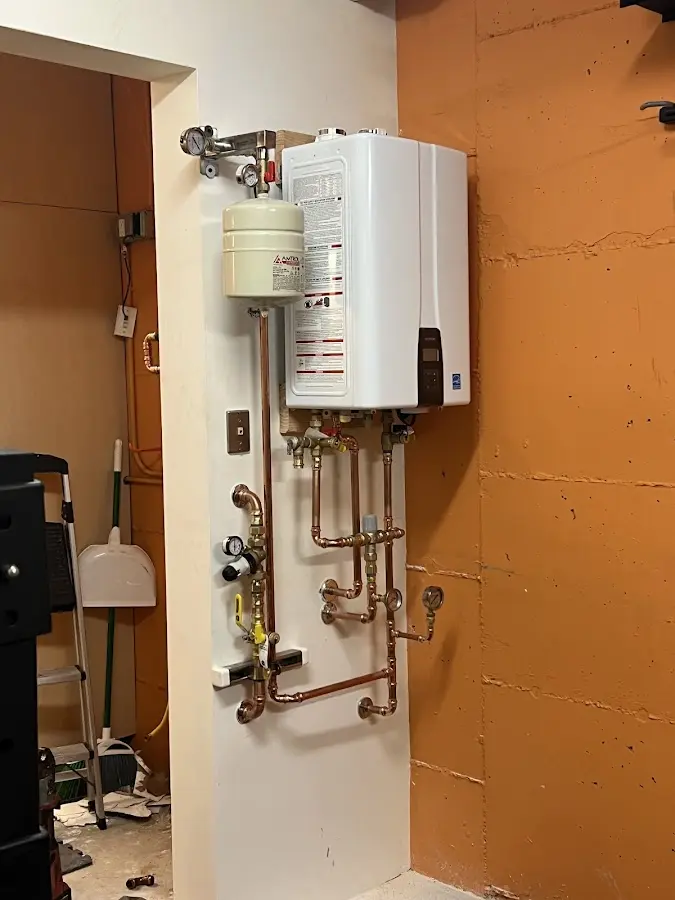 Plumbing technician inspecting water heater connections in Blairstown